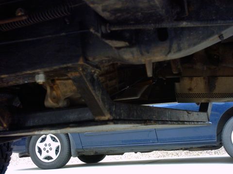 1990 Ford Bronco - The underside of a vehicle is shown, with another car visible beneath it.