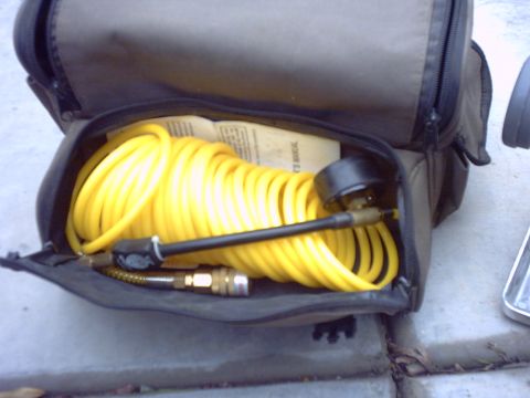 1990 Ford Bronco - Air compressor hose and gauge in a bag with a manual. The bag is open, showing the contents.