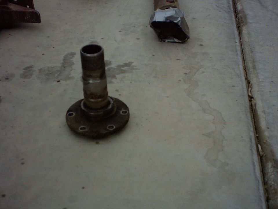 wheel hub assembly on concrete, with some metal object wrapped in tape in the background