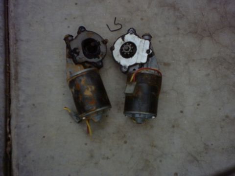 1990 Ford Bronco - Two windshield wiper motors are shown lying on a concrete surface.