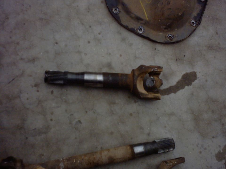 Two rusty driveshaft sections with U-joints on a concrete floor
