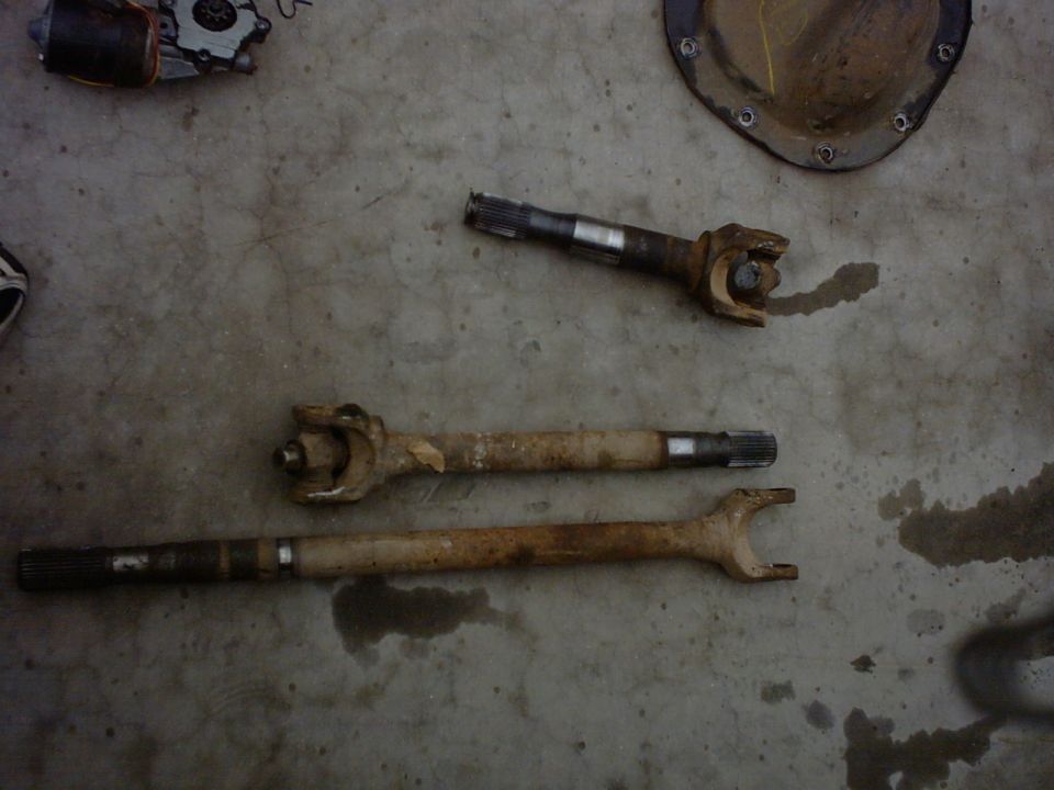 three drive shafts and a differential cover on a concrete floor