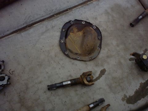 1990 Ford Bronco - Vehicle parts, including a differential cover and driveshaft, lie on a concrete surface.