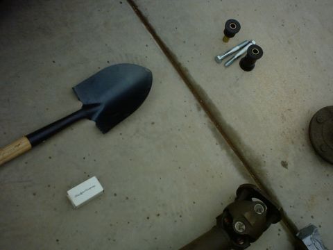 1990 Ford Bronco - Parts and a shovel laid out on a concrete surface, with some text visible on a small box.