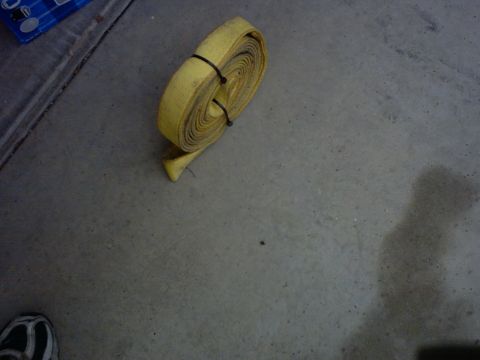 1990 Ford Bronco - Rolled yellow tow strap on concrete floor, with a blue container in the background.