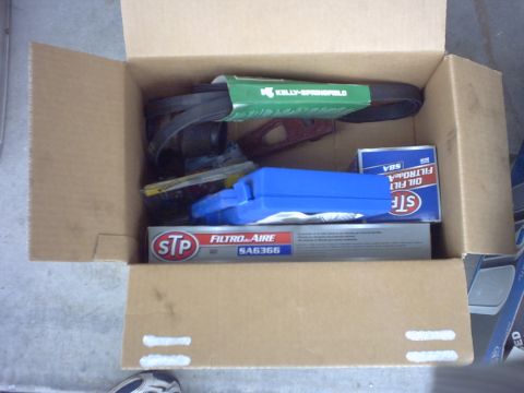 1990 Ford Bronco - A box of assorted automotive parts, including a drive belt and filters, is shown.