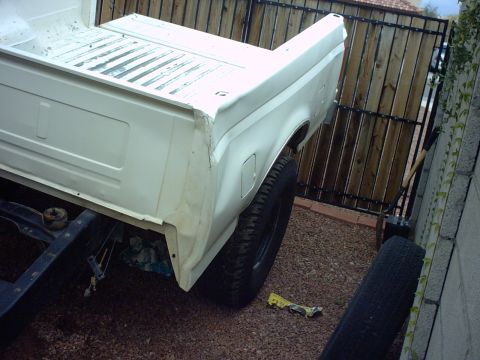 1990 Ford Bronco - The rear section of a white truck bed shows signs of wear and tear, with a spare tire visible nearby.