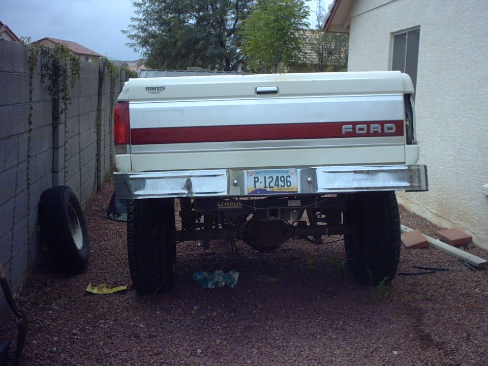 Rear view of a 1990 Ford Bronco with a red stripe on the tailgate and a license plate P-12496
