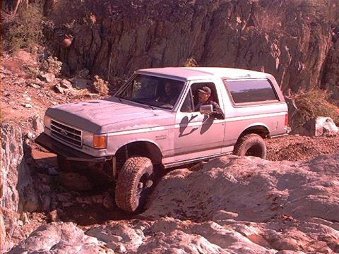 1990 Ford Bronco - Ford Bronco tackling a challenging off-road course on a sunny day.