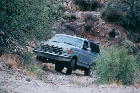 1990 Ford Bronco - A gray Ford Bronco navigates a rocky, off-road trail.
