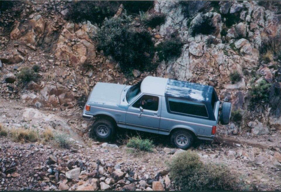 Gray SUV with a removable top on a rocky trail. Visible text: SUPERMOTORS