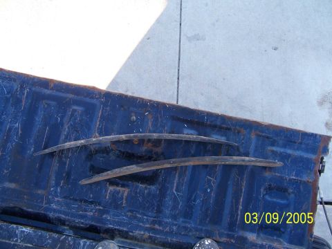 1994 Ford Bronco - Leaf springs are shown laid across the bed of a blue pickup truck.