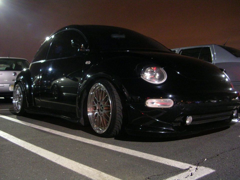 black Volkswagen Beetle with custom wheels parked at night
