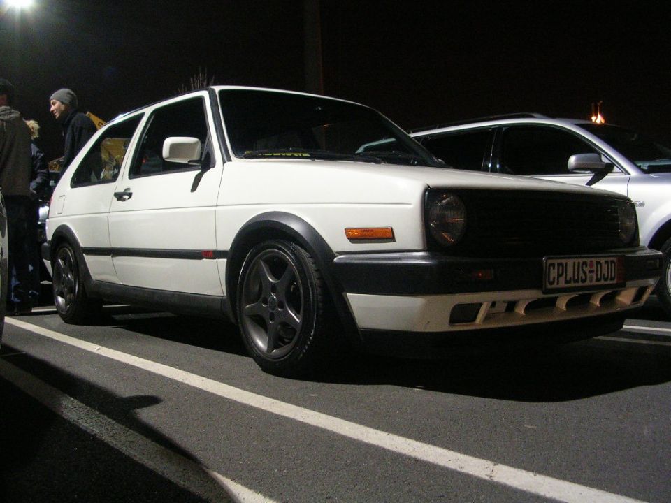 White Volkswagen Golf GTI with black grille and fender flares, parked at night