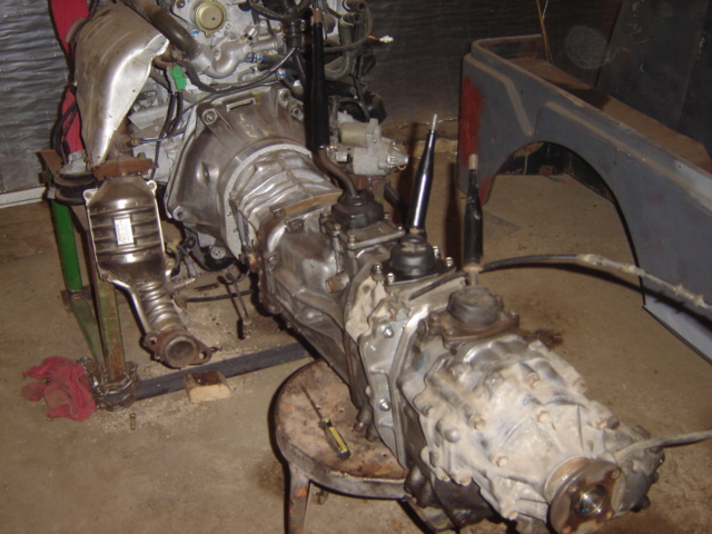 Engine and transmission assembly on a stand, with a partial vehicle fender in the background