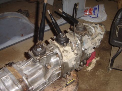 1992 Ford Bronco - A complex transmission assembly with multiple gear shift levers and a transfer case is shown in a workshop setting.