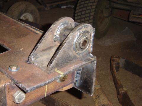 1992 Ford Bronco - Close-up of a welded metal bracket with a bolt and yellow marker, likely a vehicle part.