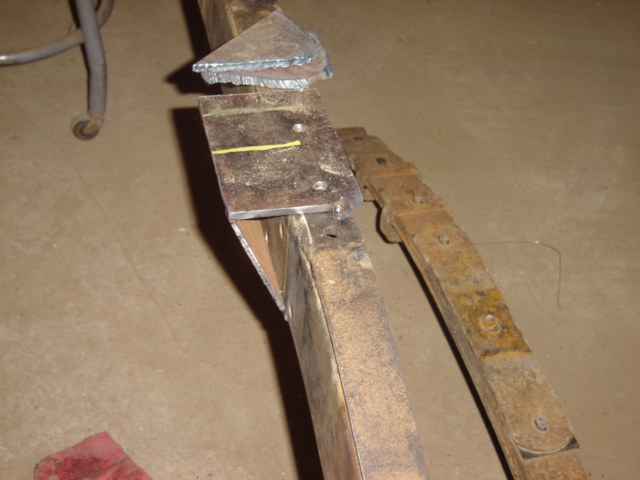 Welding bracket attached to a rusty vehicle frame section with a leaf spring visible