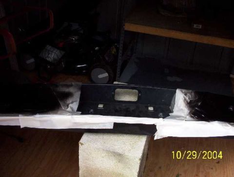 1999 Ford Crown Victoria - A black bumper part, possibly for a vehicle, is shown with masking tape and a rectangular cutout.