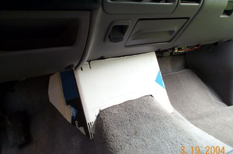 1996 Ford Bronco - A cardboard template is fitted into the passenger footwell of a gray Ford truck interior, mocking up a kick-panel or under-dash enclosure a…