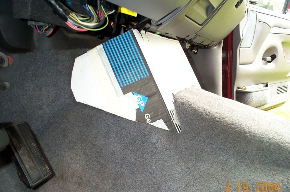 Cardboard wedge enclosure mockup on Ford truck footwell carpet with dash wiring exposed