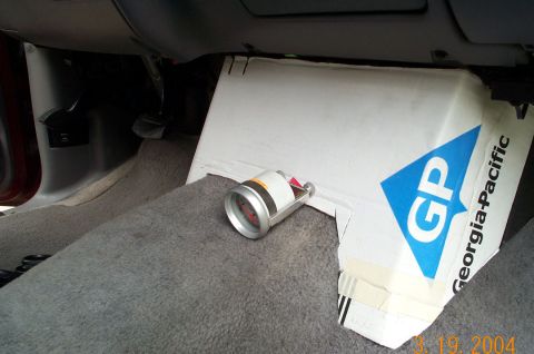 1996 Ford Bronco - Interior footwell view of a vehicle showing gray carpet and a sheet of white Georgia-Pacific 'GP' branded cardboard propped against the das…