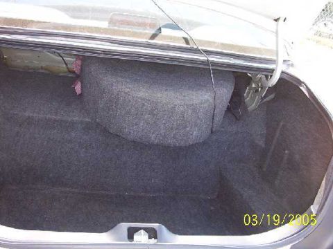 1999 Ford Crown Victoria - Interior view of a car's trunk, showing the spare tire well and carpeting. Date stamp visible.