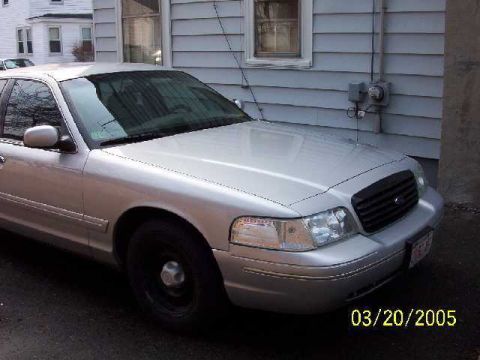 1999 Ford Crown Victoria - A silver sedan is parked in front of a house, showing its front quarter. The date 03/20/2005 is visible.