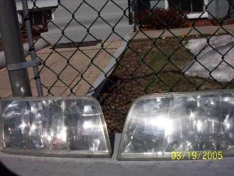 1999 Ford Crown Victoria - Two car headlights are shown, one with a date stamp of 03/19/2005 and a website address.