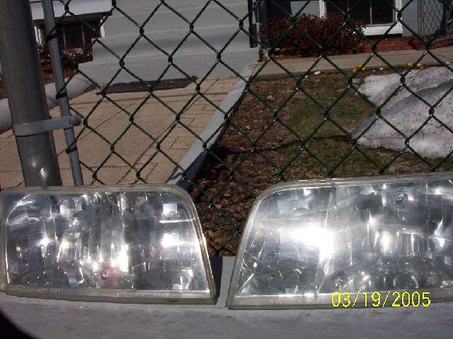 Two clear plastic car headlights with internal reflectors, one showing a date stamp