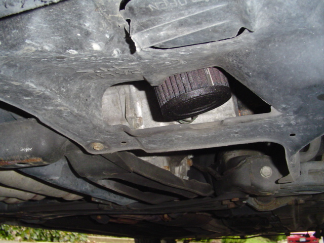 Underside of a vehicle showing an exposed black air filter and engine components