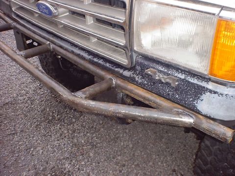 1988 Ford Bronco - Close-up of a bare, unpainted tube front bumper welded up from round steel tubing with mill markings still visible on the lower bar, mounte…