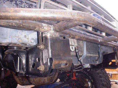 1988 Ford Bronco - Low-angle view of a shop-built bare-steel tube bumper/grille guard mounted to a Ford truck's frame horns via bolted plate brackets, the pip…