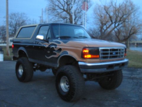 Lifted black and tan Ford Bronco with flame decals, seen from a 3/4 front angle