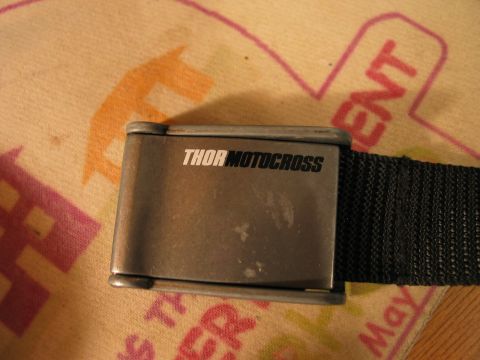 1995 Ford Bronco - A close-up of a metal buckle with the THOR MOTOCROSS logo on a black strap.