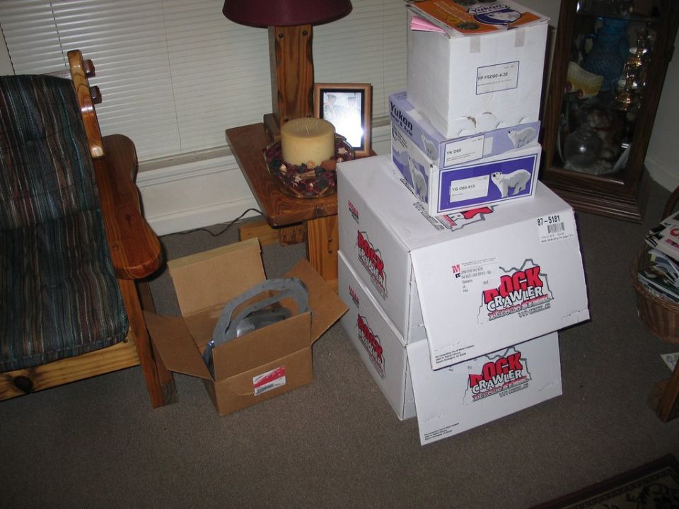 Boxes labeled Rock Crawler stacked up next to a chair and side table with a lamp and candle