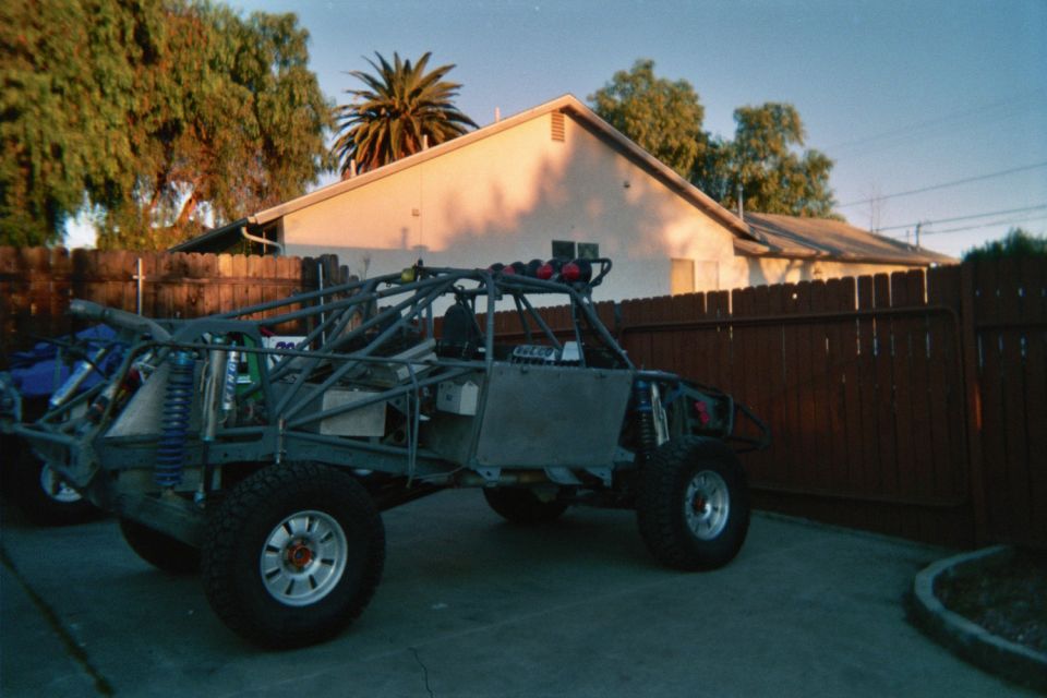 Tube-chassis off-road race buggy parked in a backyard at sunset