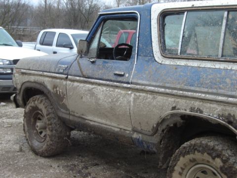 1992 Ford Bronco - This blue and white Bronco is heavily covered in mud, obscuring its details but clearly showing its side profile.