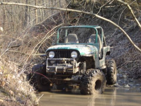 1992 Ford Bronco - This off-road vehicle is navigating through a muddy, watery terrain.