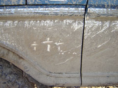 1992 Ford Bronco - A close-up view of a heavily mud-splattered vehicle door shows white markings and a watermark.