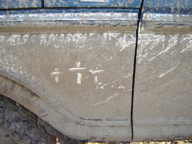 Mud-covered vehicle side with white markings and a Supermotors.net watermark