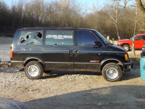 1992 Ford Bronco - A black van with damaged windows and off-road tires is parked outdoors, with another vehicle visible in the background.