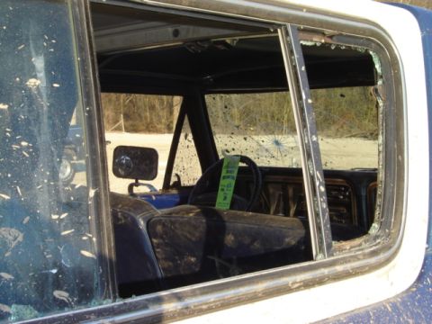 1992 Ford Bronco - Interior of a dirty, damaged SUV with broken windows. A green tag hangs from the steering wheel.