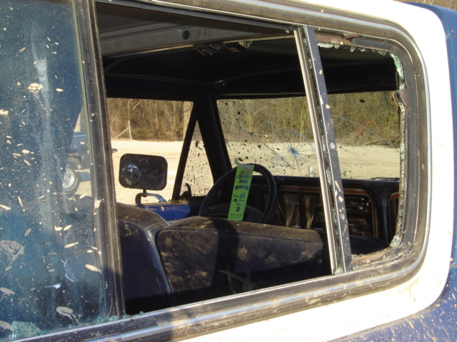 Interior view of a dirty, damaged SUV with broken windows. A green tag hangs from the steering wheel