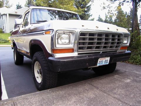 1979 Ford Bronco - A two-tone white and brown Ford Bronco SUV photographed from the right front three-quarter angle, showing its chrome grille with FORD lette…