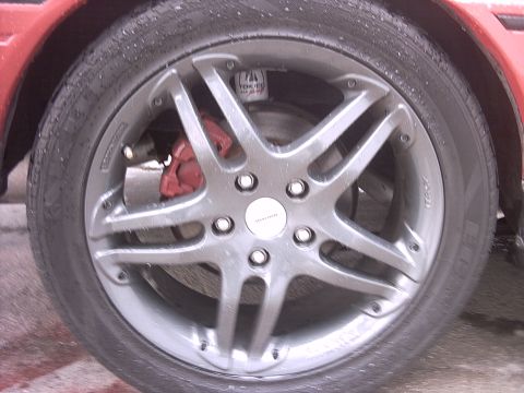 1989 Ford Probe - A close-up shot focuses on a car's wheel, revealing a red brake caliper and tire details.