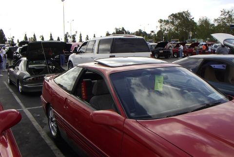 1989 Ford Probe - Red coupe with sunroof and gray coupe with open hood at a car meet.