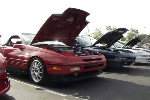 1989 Ford Probe - A line of Ford Probes, including a red 1989 model with its hood raised, are displayed at an event.