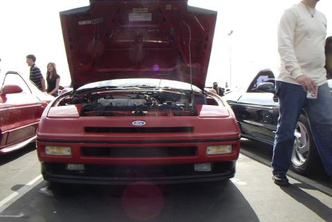 1989 Ford Probe - Front view of a red 1989 Ford Probe with its hood open, parked outdoors with other vehicles nearby.
