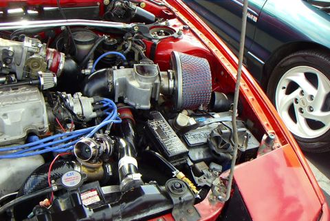 1989 Ford Probe - The engine bay of a 1989 Ford Probe shows modifications, with another vehicle visible in the background.